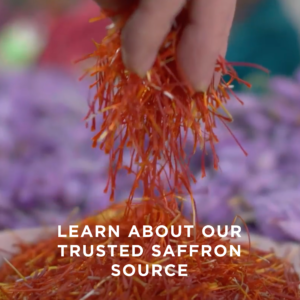 A hand pinches saffron from a dish. Text overlaid reads: "Learn about our trusted saffron source."