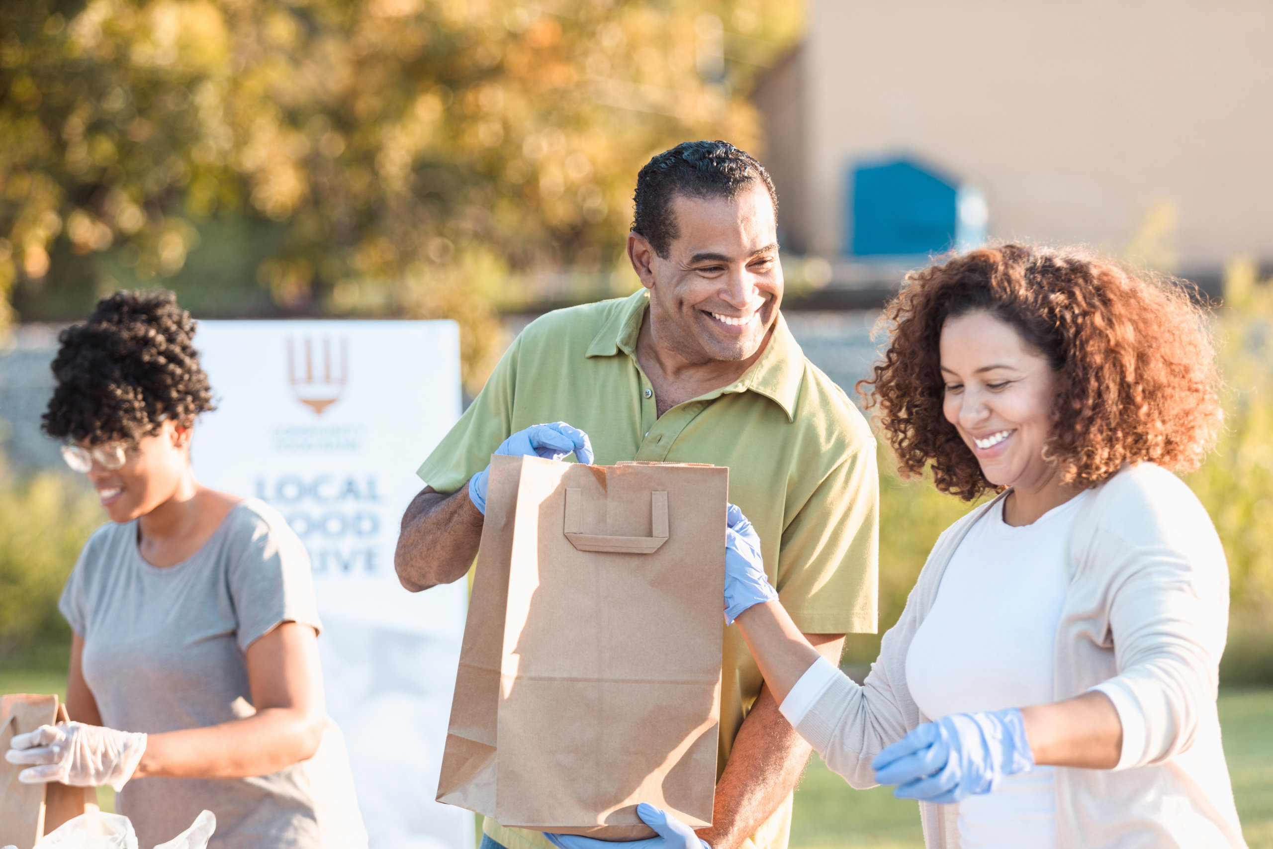 Smiling people packing paper bags.