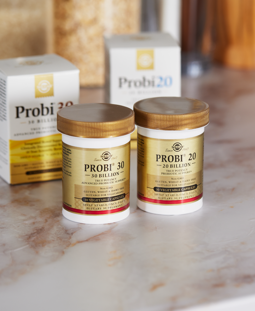 Solgar Probi 20 and Probi 30 probiotic supplements laid out on a white marble kitchen counter. In the background, array of blurry kitchen items.