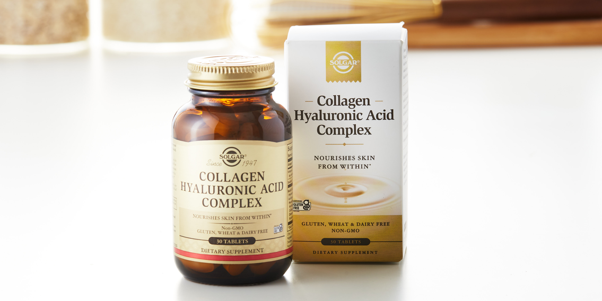 A box and bottle of Solgar Collagen Hyaluronic Acid Complex tablets on a white countertop, in front of jars of kitchen items.