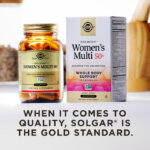 A box of Solgar One Daily Women's Multi 50+ with an amber glass bottle of the product beside it. The box and bottle are in a kitchen scene on a white countertop. The image says, "When it comes to quality, Solgar is the Gold Standard."