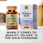 A box of Solgar One Daily Women's Multi with an amber glass bottle of the product beside it. The box and bottle are in a kitchen scene on a white countertop. The image says, "When it comes to quality, Solgar is the Gold Standard."