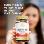 A woman holding a bottle of Solgar Ultra Potency Vitamin B12 Gummies towards the camera. The bottle is in focus but the woman is blurred with the camera's depth of field. The image says, "1500 mcg of Vitamin B12 in just one gummy."