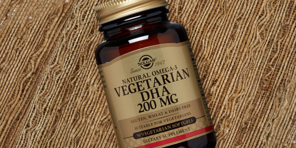 An overhead shot of a bottler of Solgar Vegetarian DHA 200mg softgels, on a textured fabric background. 