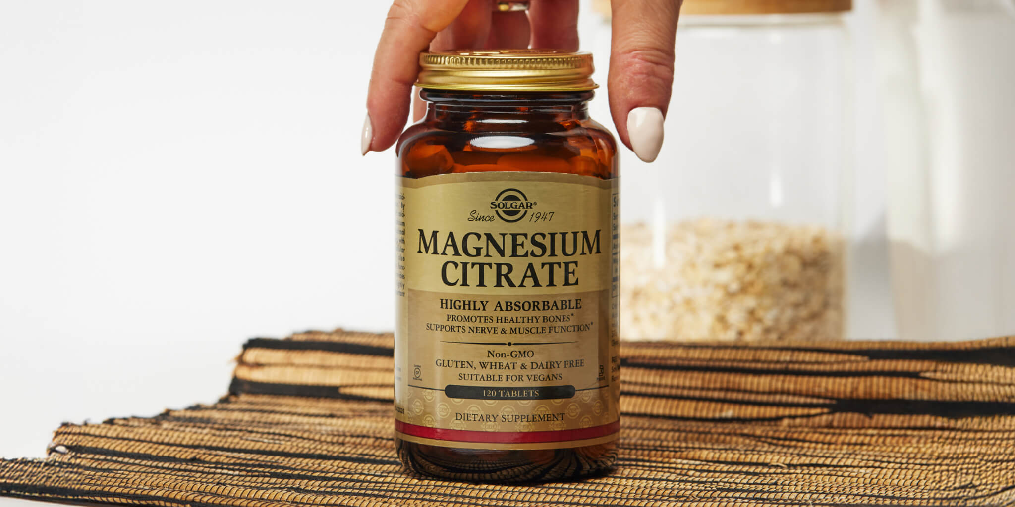 amber glass bottle on a rattan fabric with a womans hand reaching in