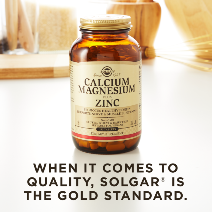 A bottle of Solgar's Calcium Magnesium Plus Zinc Tablets on a kitchen surface. Text reads "When it comes to quality, Solgar is the gold standard."