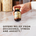 A hand holds an amber glass bottle of Solgar's Stress & Anxiety Relief tablets on top of a marble ktichen counter. Text overlaid reads: "Offers relief from occasional stress and anxiety.*"