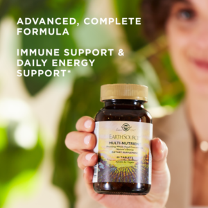 A woman holds a bottle of Solgar's Earth Source® Multi-Nutrient Tablets up to the foreground, with text reading "advanced, complete formula. Immune support and daily energy support."