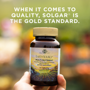 A bottle of Solgar's Earth Source® Multi-Nutrient Tablets against a backdrop of out-of-focus nature. Text reads "When it comes to quality, Solgar is the gold standard."