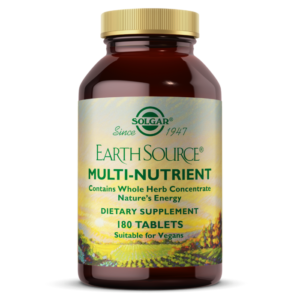 An amber glass bottle of Solgar's Earth Source Multi-Nutrient tablets, with an image of a sunny field on the label, on a white backdrop.