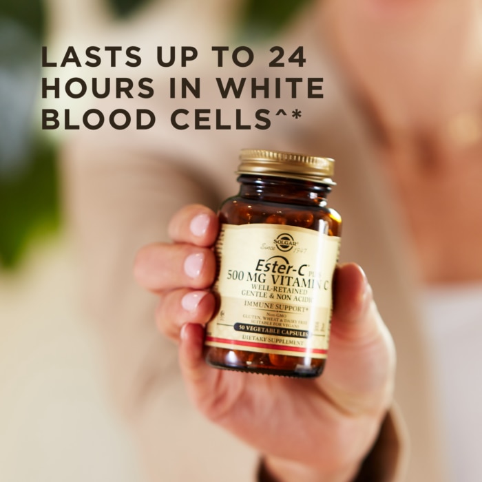 A bottle of Solgar's Ester-C® Plus 500 mg Vitamin C Vegetable Capsules (Ester-C® Ascorbate Complex) held up in a hand. Text reads "lasts up to 24 hours in white blood cells"