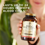 A bottle of Solgar's Ester-C® Plus 500 mg Vitamin C Vegetable Capsules (Ester-C® Ascorbate Complex) held up in a hand. Text reads "lasts up to 24 hours in white blood cells"