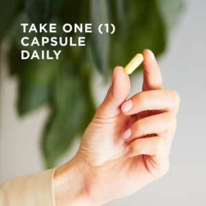 A single vegetable capsule of Solgar's B-Complex "100" supplement is held between the finger and thumb of a hand. Text reads "take one capsule daily"