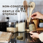 A bottle of Solgar's Gentle Iron Vegetable Capsules held on a counter by a woman. A text overlay reads: "Non-constipating. Gentle on the stomach."