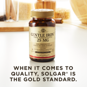 A bottle of Solgar's Gentle Iron Vegetable Capsules on a kitchen countertop. Text reads "When it comes to quality, Solgar is the gold standard."