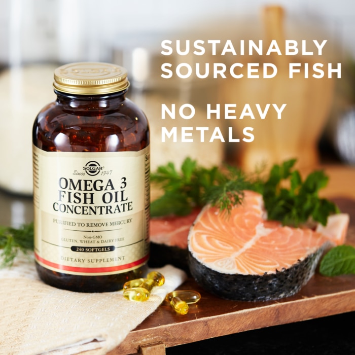 Solgar's Omega-3 Fish Oil Concentrate Softgels next to some kale and prepared fish. Text reads "sustainably sourced fish, no heavy metals"