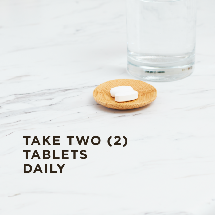 Two tablets of Solgar's Magnesium Citrate in a small wooden dish on a marble surface next to a glass of water. Text reads "take two tablets daily."