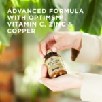 A bottle of Solgar's Skin, Nails & Hair Tablets held in two hands, with one holding the lid. Text reads "advanced formula with optimsm, vitamin C, zinc, and copper"