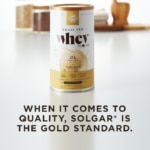 A container of Solgar's Whey To Go® vanilla-flavored protein powder on a kitchen counter, with text overlaid that reads 