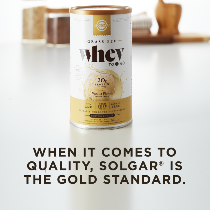 A container of Solgar's Whey To Go® vanilla-flavored protein powder on a kitchen counter, with text overlaid that reads 