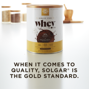 A container of Solgar's Whey To Go® chocolate-flavored protein powder on a kitchen counter, with text overlaid that reads "When it comes to quality, Solgar is the gold standard."
