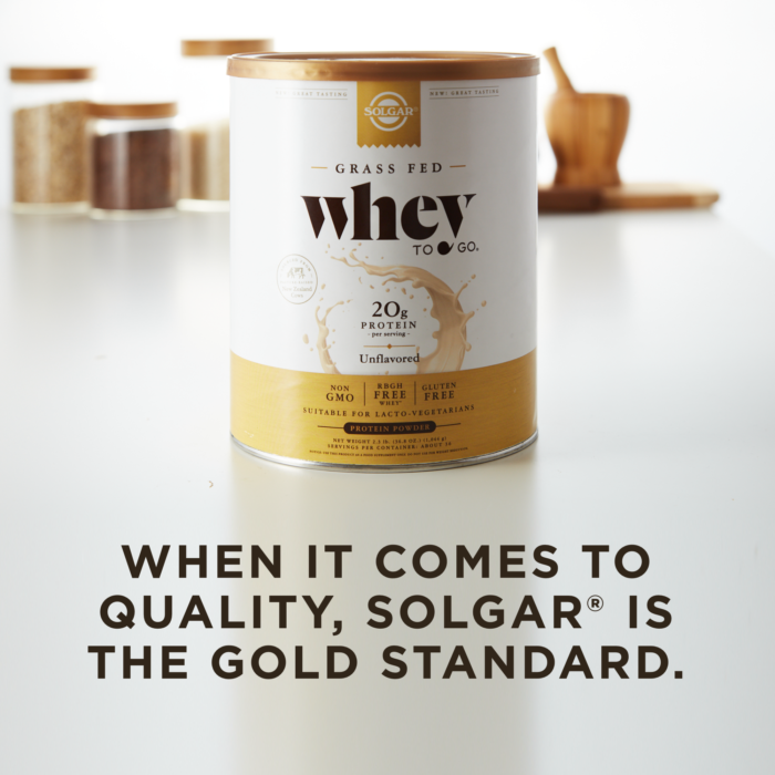 A container of Solgar's Whey To Go® plain protein powder on a kitchen counter, with text overlaid that reads 