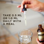 A dropper from the lid of Solgar's Liquid Vitamin D3 (Cholecalciferol) in Natural Orange flavor held above a glass of water. Text reads "take 0.5ml or 1ml daily with a meal."