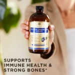 A bottle of Solgar's Liquid Calcium Magnesium Citrate with Vitamin D3 - Natural Blueberry Flavor being held in the foreground. Text reads "supports immune health and strong bones"