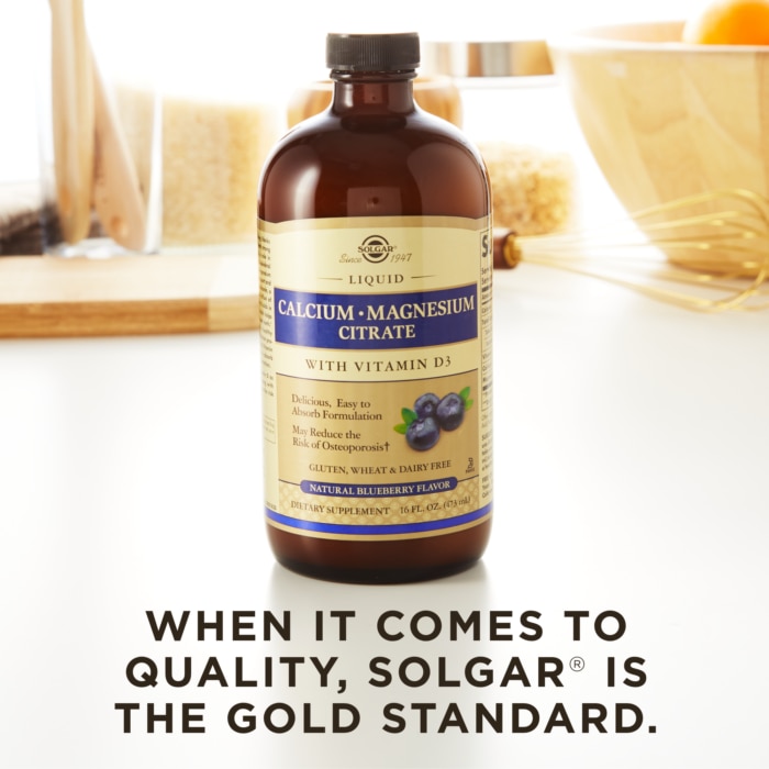 A bottle of Solgar's Liquid Calcium Magnesium Citrate with Vitamin D3 - Natural Blueberry Flavor on a kitchen surface. Text reads "When it comes to quality, Solgar is the gold standard."