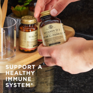Solgar's Vitamin D3 Cholecalciferol softgels held in a persons hands, with other Solgar products on a table in the background. Text reads "Support a healthy immune system*"
