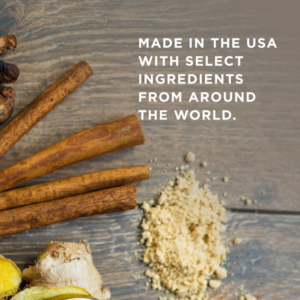 Cinammon sticks and ginger laying on a wooden table, with white text overlaid reading: "Made in the USA with select ingredients from around the world"